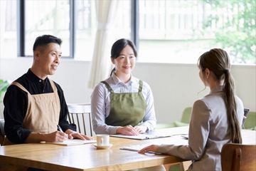 どんな経費が補助金で補助されるのかスタッフに確認するご夫婦の画像。